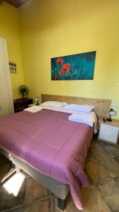 un grande letto in una stanza con una coperta viola di da sciuri case vacanza barisciano a Barisciano
