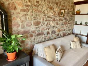 a couch in a room with a stone wall at El Portal de Vilafamés in Vilafamés