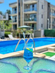 a drink in a glass on the edge of a swimming pool at Apollo Plus Cottages in Ureki