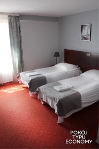 2 łóżka w pokoju hotelowym z czerwonym dywanem w obiekcie Hotel Gordon w Warszawie