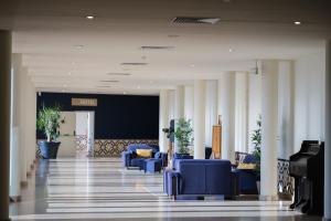 a lobby with blue chairs and a piano at Vilar Oporto Hotel in Porto