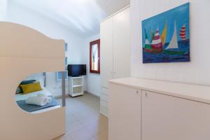 Cette chambre blanche dispose d'un lit et d'une télévision. dans l'établissement Villette con piscina zona Porto Pino, à SantʼAnna Arresi