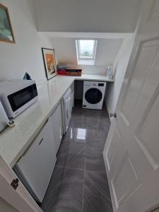 a small white kitchen with a microwave and a sink at Oakenclough Hall in Macclesfield