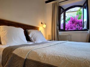 a bed with white pillows and a window with purple flowers at Villa Arca in Les Arcs sur Argens