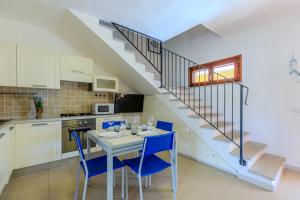 サンタンナ・アッレージにあるPorto Pino, Garden and Poolのキッチン、ダイニングルーム(テーブル、青い椅子付)
