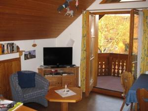 a living room with a television and a table at Appartement in Wittenschwand mit Garten und Grill und Panoramablick in Wittenschwand