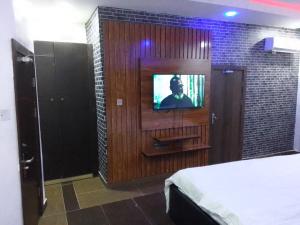 Habitación con cama y TV en la pared. en Exclusive mansion lekki phase 1, en Ilado