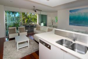 uma cozinha com um lavatório e uma sala de estar em The Beach Cabarita em Cabarita Beach