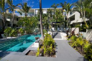 una piscina con palmeras y un edificio en The Beach Cabarita en Cabarita Beach