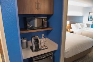 a small hotel room with a bed and a microwave at Holiday Inn Express Hotel & Suites East Lansing by IHG in East Lansing +34 photos