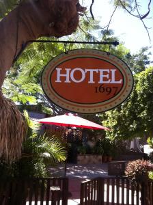 a sign for a hotel with a table and an umbrella at Hotel 1697 Loreto in Loreto