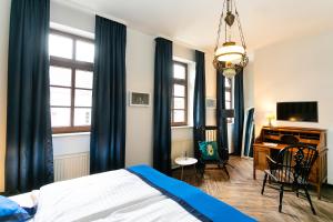 1 dormitorio con cortinas azules, 1 cama y escritorio en Landhaus Danielshof, en Bedburg