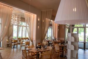 a restaurant with tables and chairs and a large chandelier at Hotel Anna Villa in Balatonföldvár