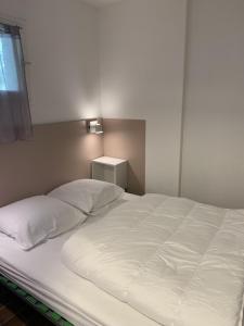 un grande letto bianco in una stanza con finestra di Appartement Domaine de la Coudouliere + piscine (mai à octobre) a Six-Fours-les-Plages