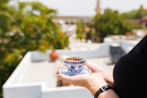 a person holding a blue and white cup of coffee at Homelike Guest House in Kyrenia