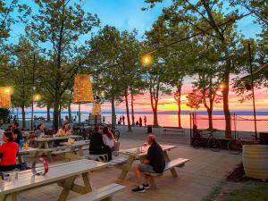 a group of people sitting at picnic tables near the beach at Hotel Anna Villa in Balatonföldvár