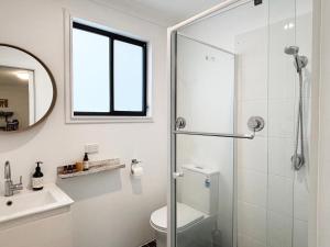 Un baño con ducha, inodoro y lavabo. en Bowerbird Cottage, en Camberwarra
