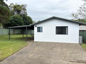 una casa con un garaje blanco en Bowerbird Cottage, en Camberwarra
