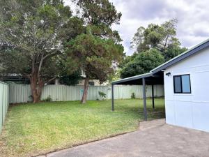 una casa con un garaje blanco y un patio en Bowerbird Cottage, en Camberwarra 2 fotos más