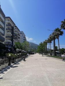 an empty street with palm trees and a building at VERA APARTMENT in Vlorë