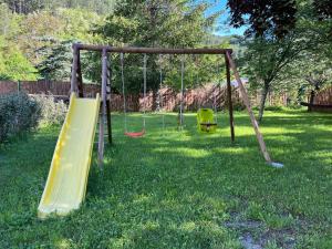 un parque infantil con dos columpios en el césped en La maison Valban, en Veynes