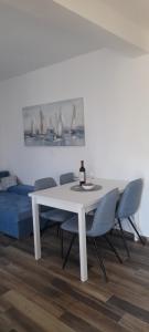 a white dining table with chairs and a bottle of wine at Holiday house Stela in Gdinj