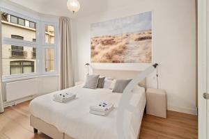 biała sypialnia z dużym białym łóżkiem i oknem w obiekcie Kolonel - Charmant & lichtrijk app aan zee 4p w mieście Blankenberge