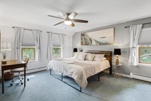 Schlafzimmer mit einem Bett, einem Schreibtisch und Fenstern in der Unterkunft River Front Home In the Heart of Ithaca in Ithaca