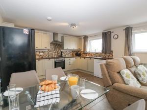 a living room with a glass table and a kitchen at Top Lodge in Llanvair Discoed