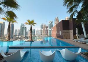 a swimming pool with chairs and palm trees in a city at Phenomenal 1BR at Marina Gate 2 in Dubai Marina by Rich Stay in Dubai