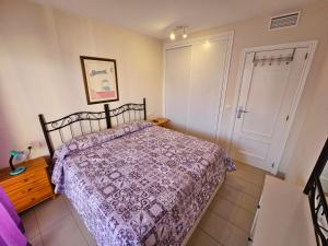 um quarto com uma cama com um edredão roxo em Apartamento El Gemelos em Cala de Finestrat
