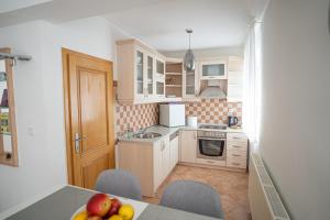 a kitchen with white cabinets and a table with fruit at Apartman A&S in Tomislavgrad