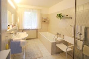 a white bathroom with a tub and a sink at Ferienhaus Glücksfall in Jesteburg