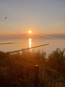 a sunset over the ocean with a pier in the water at Sonia Pearl Apartament z parkingiem in Sianozety