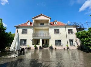 a large building with an umbrella and a table and chairs at Villa Agos in Shkodër