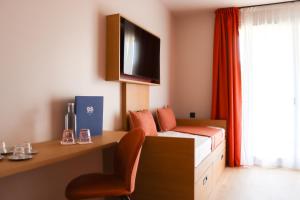 a room with a bed and a desk and a tv at Hôtel Best of Both - Divonne-les-Bains in Divonne-les-Bains