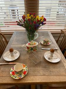 a table with plates and cups and a vase of flowers at Herne Bay Central - 2 minutes from beach apartment in Herne Bay