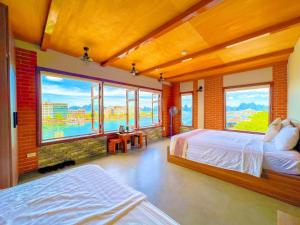sypialnia z 2 łóżkami i dużymi oknami w obiekcie Cánh Buồm Homestay - Tuần Châu w Ha Long