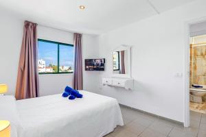 ein weißes Schlafzimmer mit einem weißen Bett und einem Fenster in der Unterkunft Club Tarahal in Puerto de la Cruz