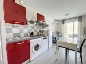 a kitchen with red cabinets and a washing machine at 3284 - appartement 4 couchages avec piscine in Argelès-sur-Mer