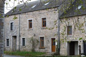 an old stone building with brown doors and windows at Maisons de vacances Le Vieux Marronnier in Dinant