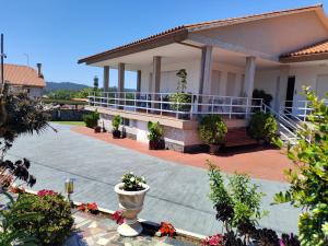 a house with a porch and a courtyard with flowers at Pension Asun Sanxenxo in Sanxenxo
