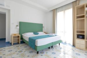 una camera con un grande letto con testiera verde di Napolit'amo Hotel Medina a Napoli