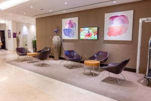une salle d'attente avec des chaises et des peintures murales dans l'établissement Premier Inn Abu Dhabi Airport Business Park, à Abu Dhabi
