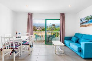 ein Wohnzimmer mit einem blauen Sofa und einem Tisch in der Unterkunft Club Tarahal in Puerto de la Cruz