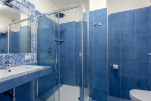 ナポリにあるNapolit'amo Hotel Medinaの青いタイル張りのバスルーム(シンク、シャワー付)