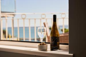 uma garrafa de vinho e um copo no peitoril da janela em Bayfort Sea Studio - Comfortable Couples Retreat with Stunning Coastal Views em Torquay