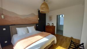 a bedroom with a bed with white sheets and a pendant at La Demoiselle in Les Ponts-de-Cé