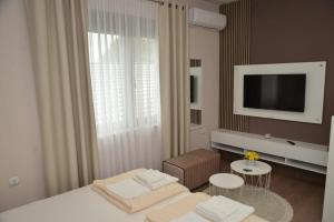 Schlafzimmer mit einem Bett, einem TV und einem Tisch in der Unterkunft Apartmani Tomić in Kladovo