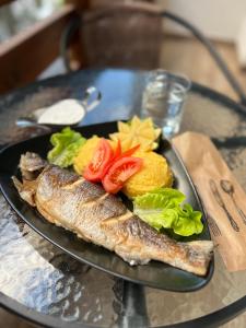 a plate of fish and vegetables on a table at Hotel Transalpin in Obarsia-Lotrului